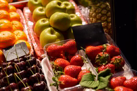 Colorful fruit display showcasing fresh strawberries, cherries, green apples, and vibrant oranges at a local market during early afternoon hours photo