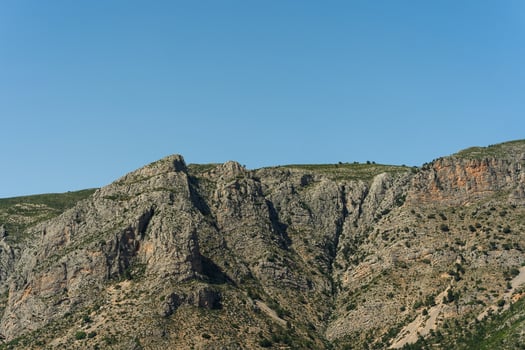 A plane flying over a mountain with a blue sky photo