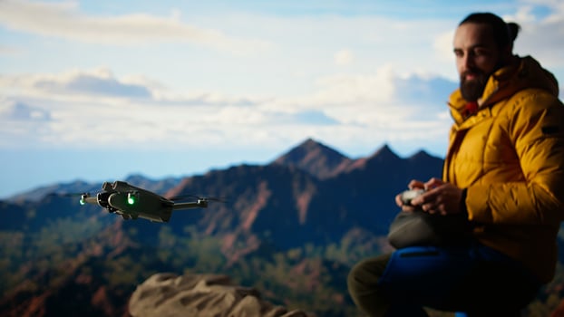 Traveler balances adventure and creating content by filming with his drone, recording the aerial view of a beautiful mountain range. Breathtaking landscape scenery videography. Camera A. photo