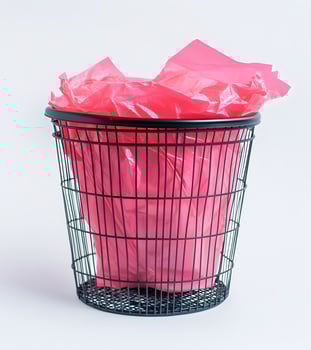 Pink plastic trash bag inside a black metal wastebasket. photo