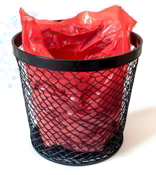 Red plastic trash bag inside a black metal mesh waste bin. photo