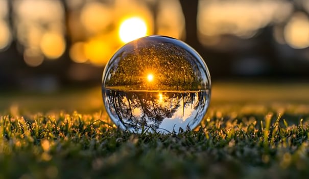 Crystal ball reflecting a golden sunset over a field of green grass. photo