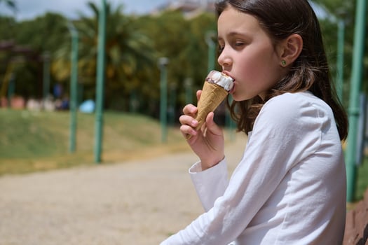 Young Girl Eating Ice Cream Cone Outdoors in a Park Setting photo