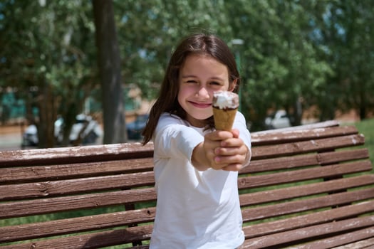Smiling Young Girl Enjoying Ice Cream in a Park on a Beautiful Summer Day photo