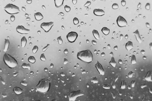 Raindrops on a window glass with a blurred gray sky in the background. photo