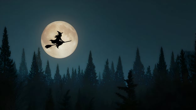 A Halloween night scene shows a witch silhouette flying on her broom across a huge full moon photo