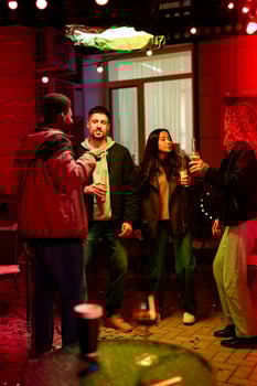 Friends enjoying an evening gathering with drinks outdoors in a vibrant setting with festive lights photo