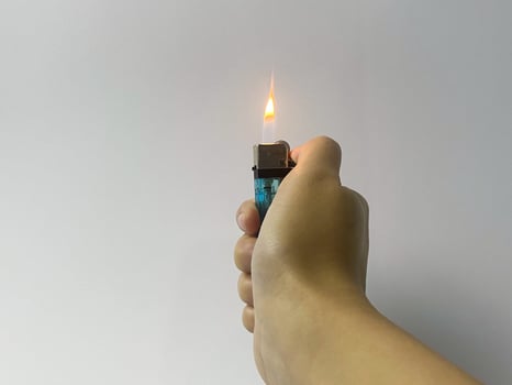 Cropped hand of a woman's hand turning on a lighter on white background. photo