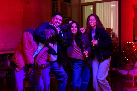 Group of friends enjoying a joyful evening at a lively social gathering in a cozy venue with colorful lighting photo
