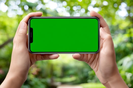 Hands holding smartphone with green screen in park photo