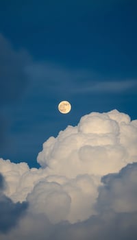 full moon is seen through the clouds photo