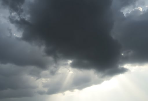 plane flying through a cloudy sky with sunbeams photo