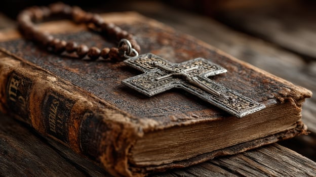 Antique book with a silver cross resting on a weathered wooden surface during a serene afternoon photo
