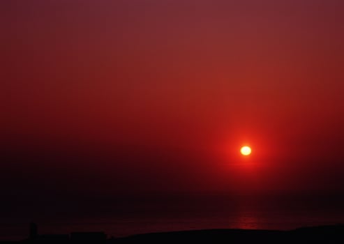 the sun sets over the ocean in a red sky photo