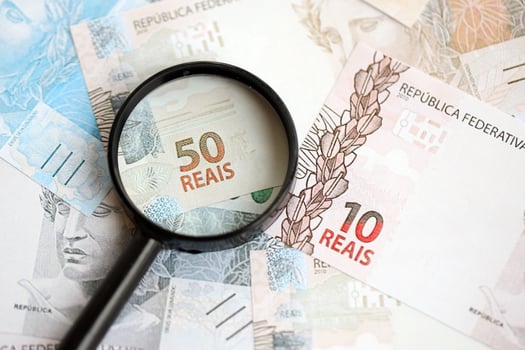 Brazilian reais banknotes and magnifying glass. The current Brazil real money bills and loupe photo