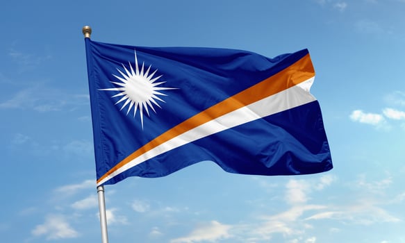Marshall Islands national flag with radiant star and diagonal stripes waving in the tropical sky photo