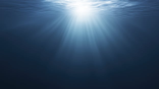 Underwater scene showcasing sunlight penetrating the surface, creating a serene atmosphere with gentle waves and deep blue hues, evoking tranquility and calmness in aquatic environments photo