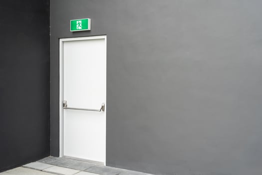 Emergency Exit Door with Green Sign on Grey Wall for Safety and Evacuation Concept. Copy space photo