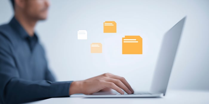 Professional man working on laptop with digital file icons floating above, showcasing modern technology and efficient data management in a contemporary workspace photo