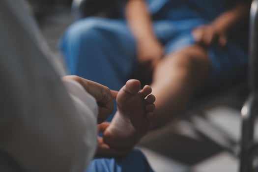 A person in blue scrubs is holding a foot photo