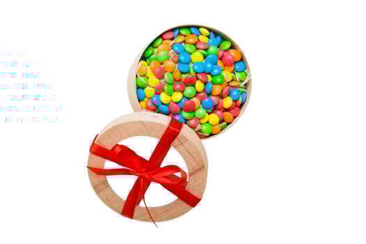 Set of different sweet candy in paper box with a satin ribbon on a colored background. photo