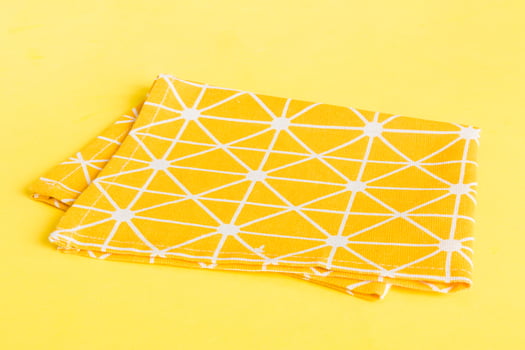 top view with yellow empty kitchen napkin isolated on table background. Folded cloth for mockup with copy space, Flat lay. Minimal style photo