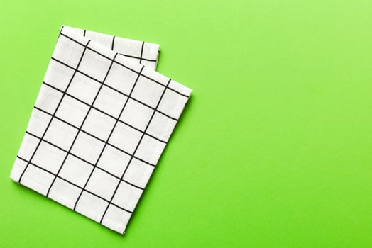 top view with white empty kitchen napkin isolated on table background. Folded cloth for mockup with copy space. Minimal style photo