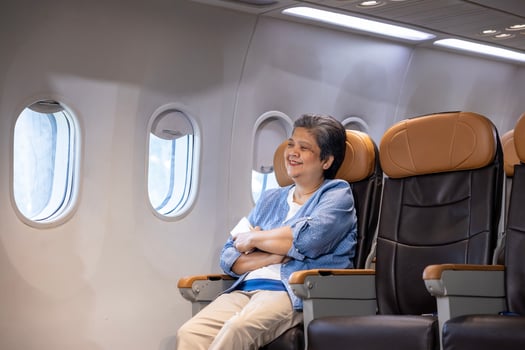Asian senior woman traveler is sitting comfortably in the aircraft while looking out the window for retirement travel trip alone in economy class photo