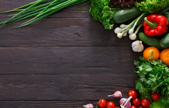 Border of fresh organic vegetables on wood background. Healthy natural food on rustic wooden table with copy space. Garlic, lettuce, carrot, pepper, zucchini and other cooking ingredients top view photo