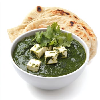 A bowl of palak paneer, with creamy spinach and paneer cheese, cooked in a flavorful gravy, served with naan bread, isolated on clean white background. photo