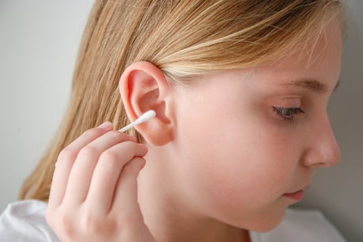 The child cleans the auricle with a cotton swab photo