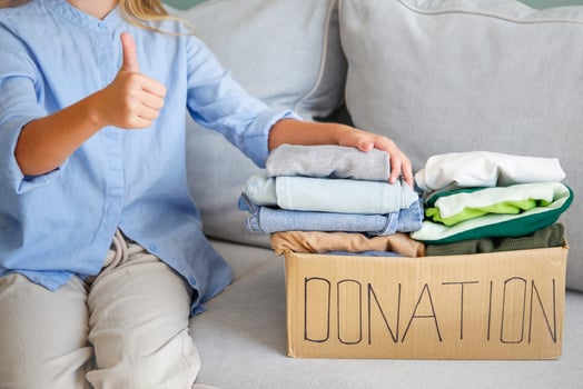 girl puts clothes in donation box photo