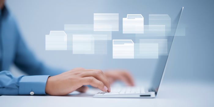 Person using laptop with floating digital file icons representing data management and organization in a modern workspace with copy space for text photo