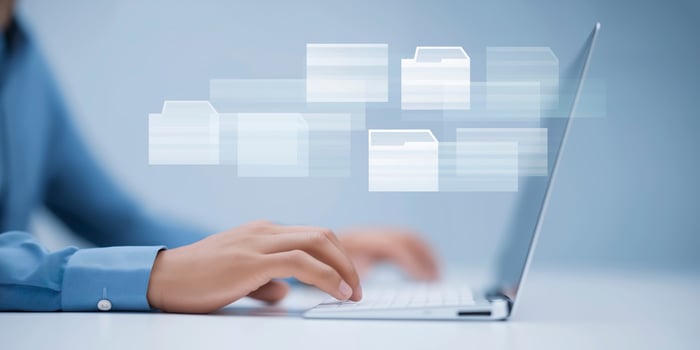 Person using laptop with digital file icons floating above, representing data management and organization in a modern workspace with copy space photo