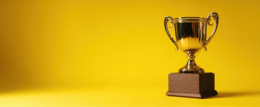 The shiny trophy symbolizing achievement and success against a vibrant yellow background. photo
