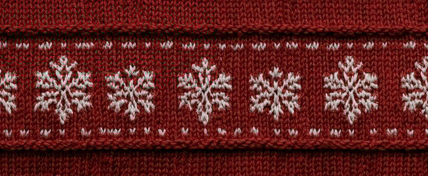 The vibrant knit fabric featuring intricate snowflake designs in red and white. photo