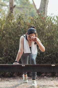 A woman is standing on a bench with her head down photo