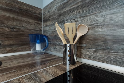 A wellorganized kitchen counter that features a variety of wooden utensils along with a beautifully crafted pitcher placed on it, showcasing a rustic and inviting atmosphere photo