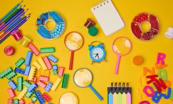 Collection of colorful school supplies, building bricks, letters, and learning items scattered on a yellow background. Play and education concept. photo