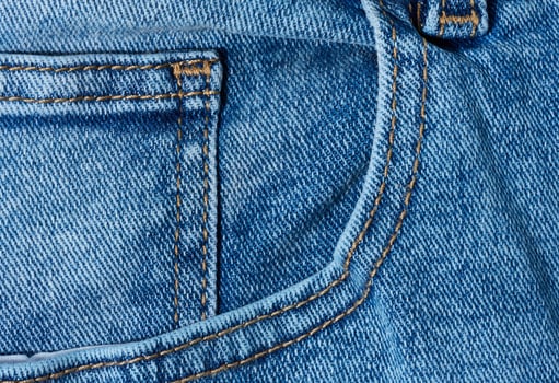 Blue denim jeans showing a front pocket corner with distinct orange stitching detail photo