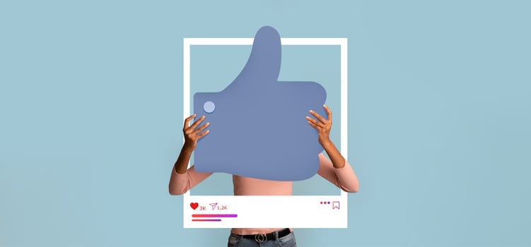 A person holds a large thumbs up symbol in front of a light blue background, symbolizing online approval. This display encourages interaction on social media platforms for content creators. photo