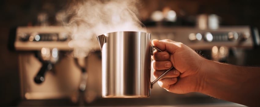 A person holding a coffee pot with steam coming out photo