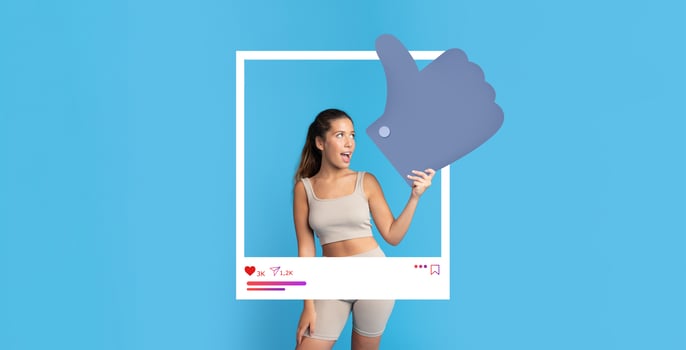 A social media influencer poses playfully with a thumbs up against a bright blue background. The lively atmosphere enhances her excitement for online engagement and content creation. photo