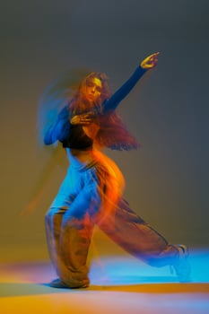Expressive jazz-funk dancer captured mid-motion with glowing neon lights and colorful blur, showcasing rhythm, grace, and bold energy in a modern, creative dance studio scene. photo