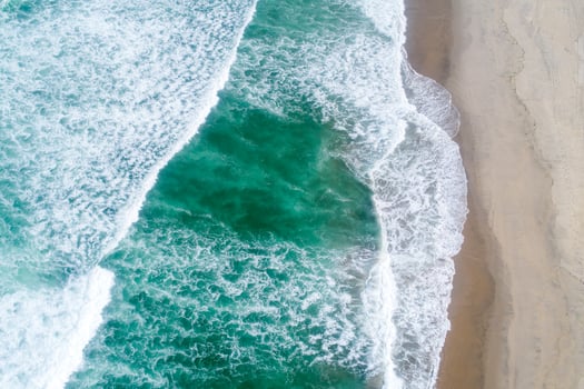 top down drone photography breaking surf on a wide beach with people Aerial image from a drone photo