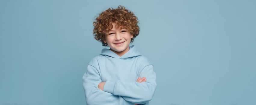 The cheerful boy with curly hair wearing a blue hoodie and smiling confidently. photo