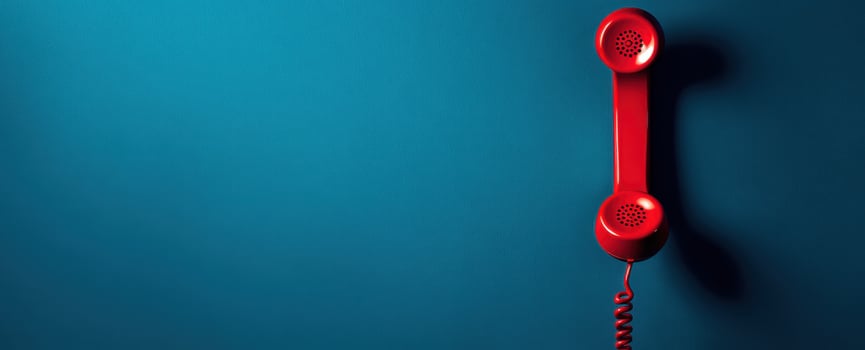 The vibrant red telephone hanging against a blue background. photo