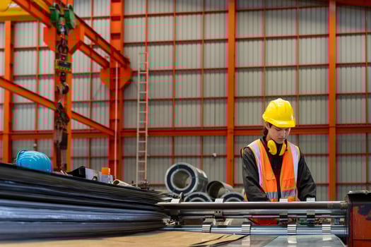 Asian industrial worker checking the setup value of metal sheet roll forming machine inside roof factory for safety industry construction photo