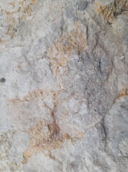 Close-up image of a rough, weathered rock surface showcasing natural textures, cracks, and varied shades of brown and gray. photo