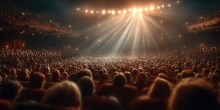 Crowded theater audience eagerly anticipates performance with lights shining on stage at night photo